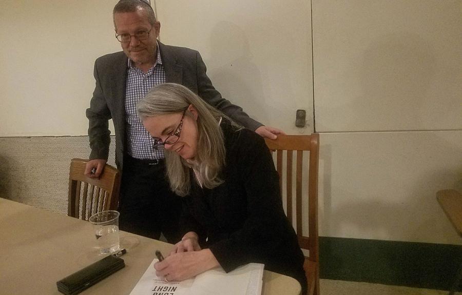 Andrea Pitzer signing a book with Jonathan Boyarin standing behind